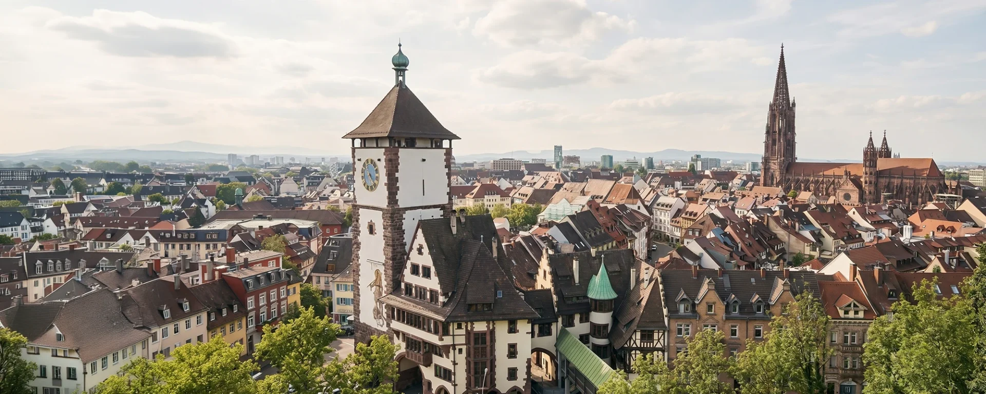 Blick über die Altstadt von Freiburg mit einem historischen Stadttor vorne und dem Freiburger Münster rechts