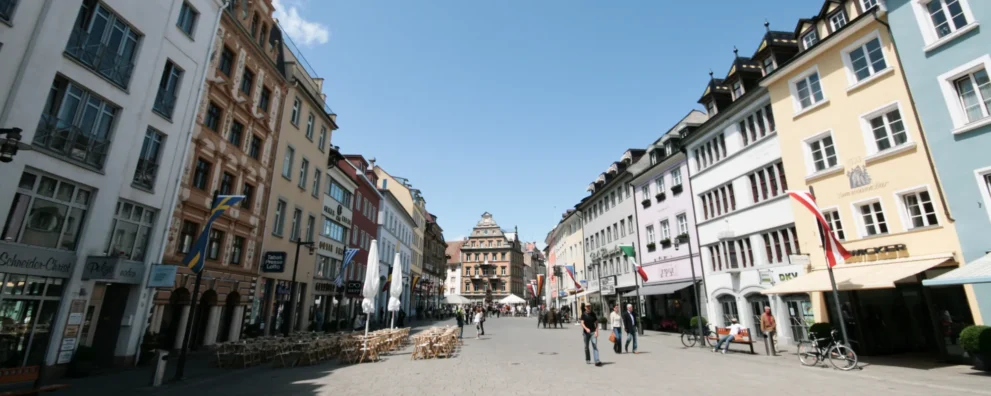 Marktstätte in der Konstanzer Altstadt bei Tag mit bunten Häuserfronten und blauem Himmel